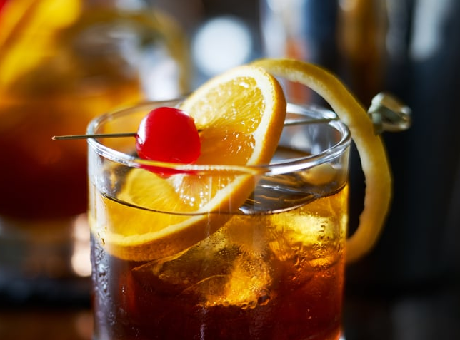 Old Fashioned servido en vaso bajo con hielo grande y piel de naranja