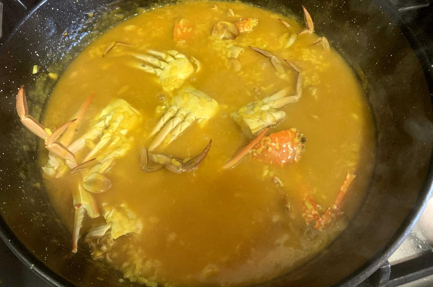 Arroz meloso con cangrejo azul y sepia, presentado en cazuela de barro con trozos visibles de marisco