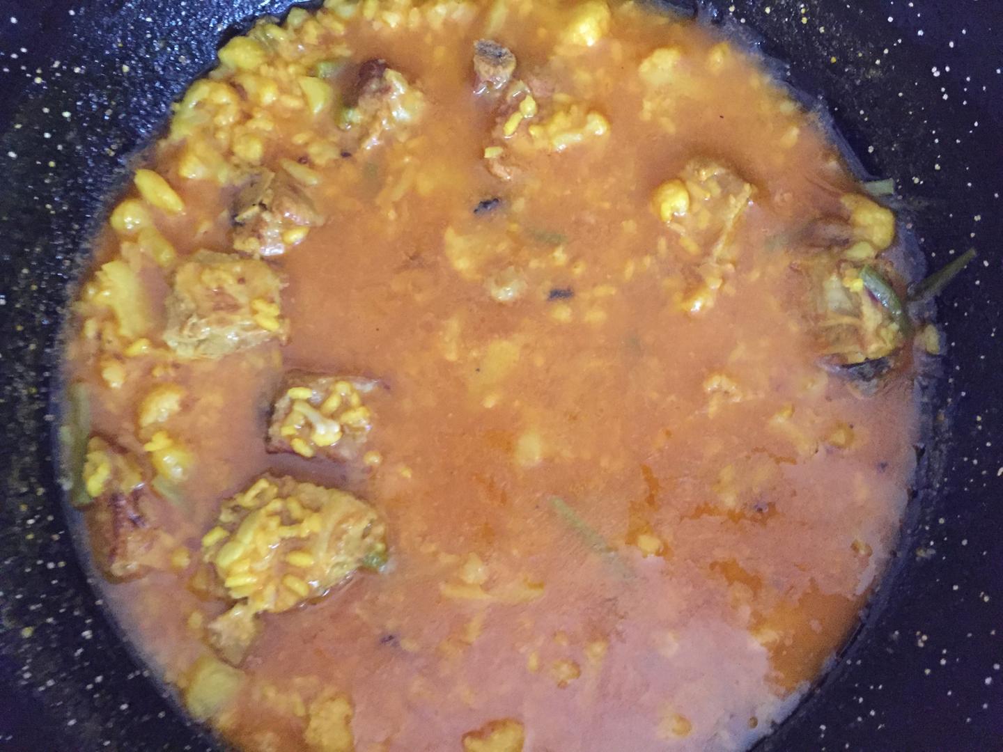 Arroz meloso de costillas de cerdo con col y ajos tiernos servido en cazuela de barro con caldo dorado