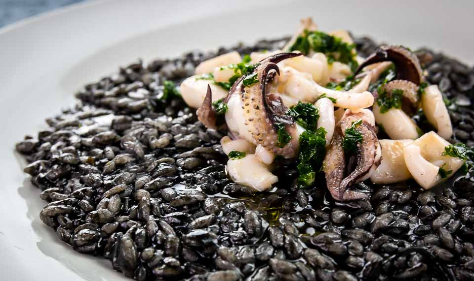 Risotto al Nero di Sepia negro intenso con sepia tierna servido en plato