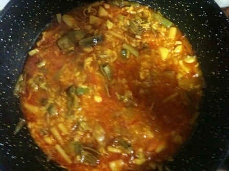 Arroz meloso de sepia y alcachofas presentado en cazuela de barro, con trozos de sepia y láminas de alcachofa