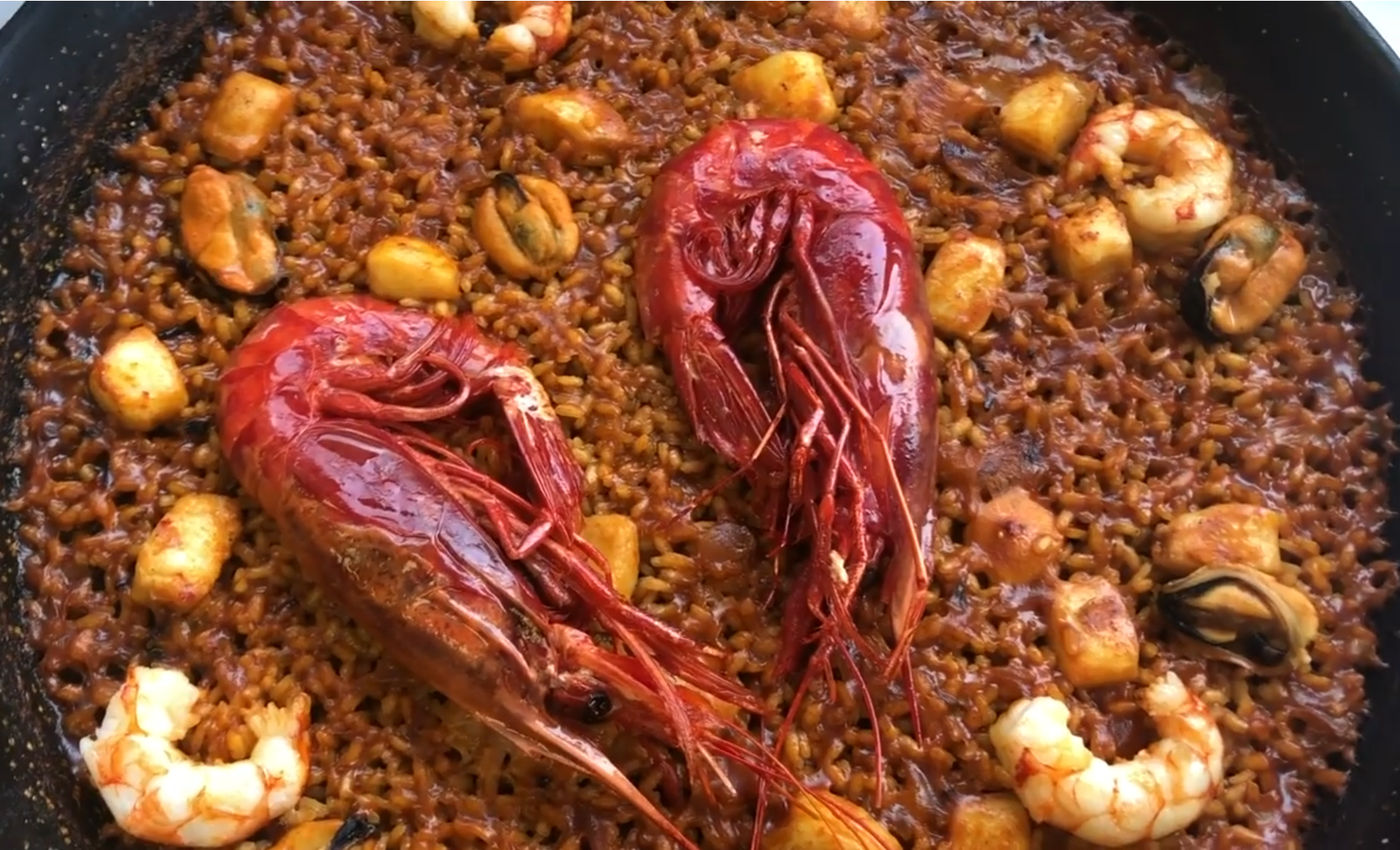 Paella de carabineros servida con arroz brillante y marisco rojo intenso