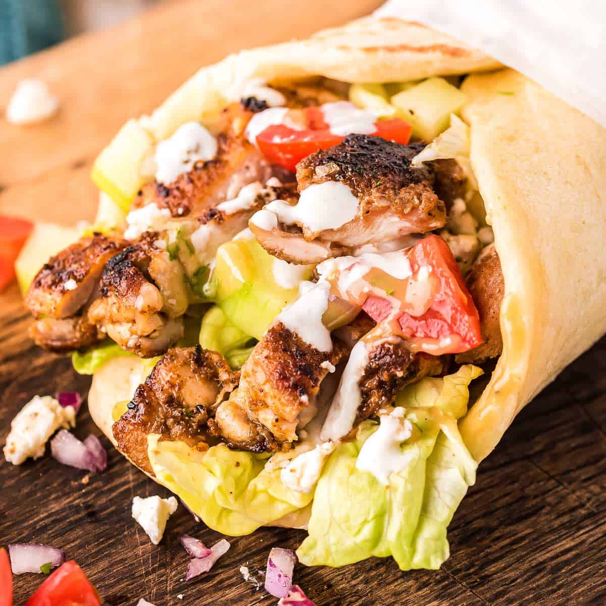 Shawarma de pollo servido en pan de pita con verduras y salsa de yogur