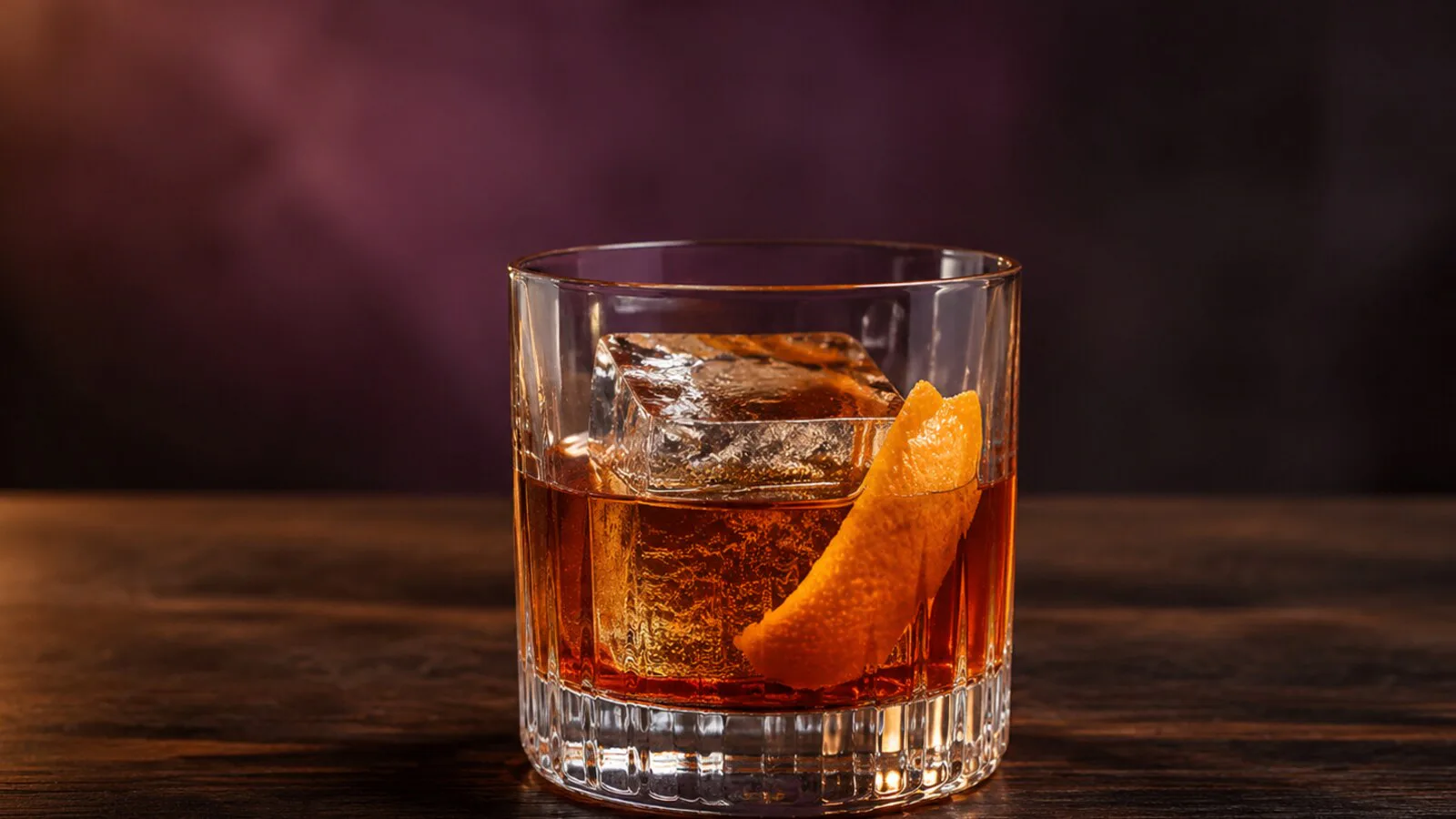 Ciruela Ahumada Old Fashioned ámbar con hielo grande y piel de naranja