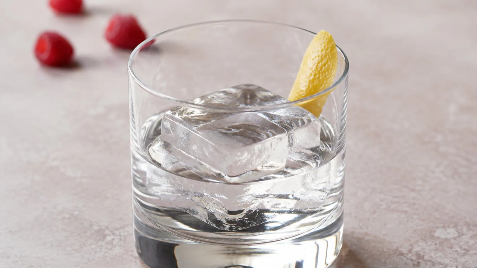 Aguardiente transparente de frambuesa servido sobre un gran cubo de hielo