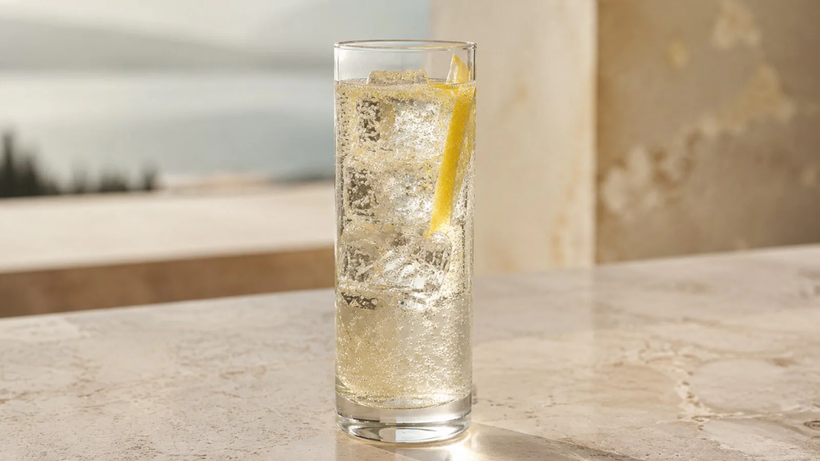 Grappa Tónica clara y burbujeante con piel de limón en vaso alto