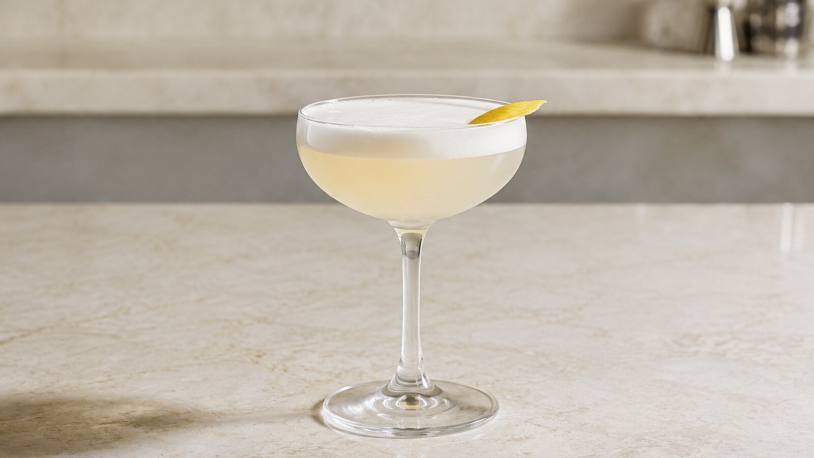 Kirsch Sour pálido con espuma fina en copa coupé