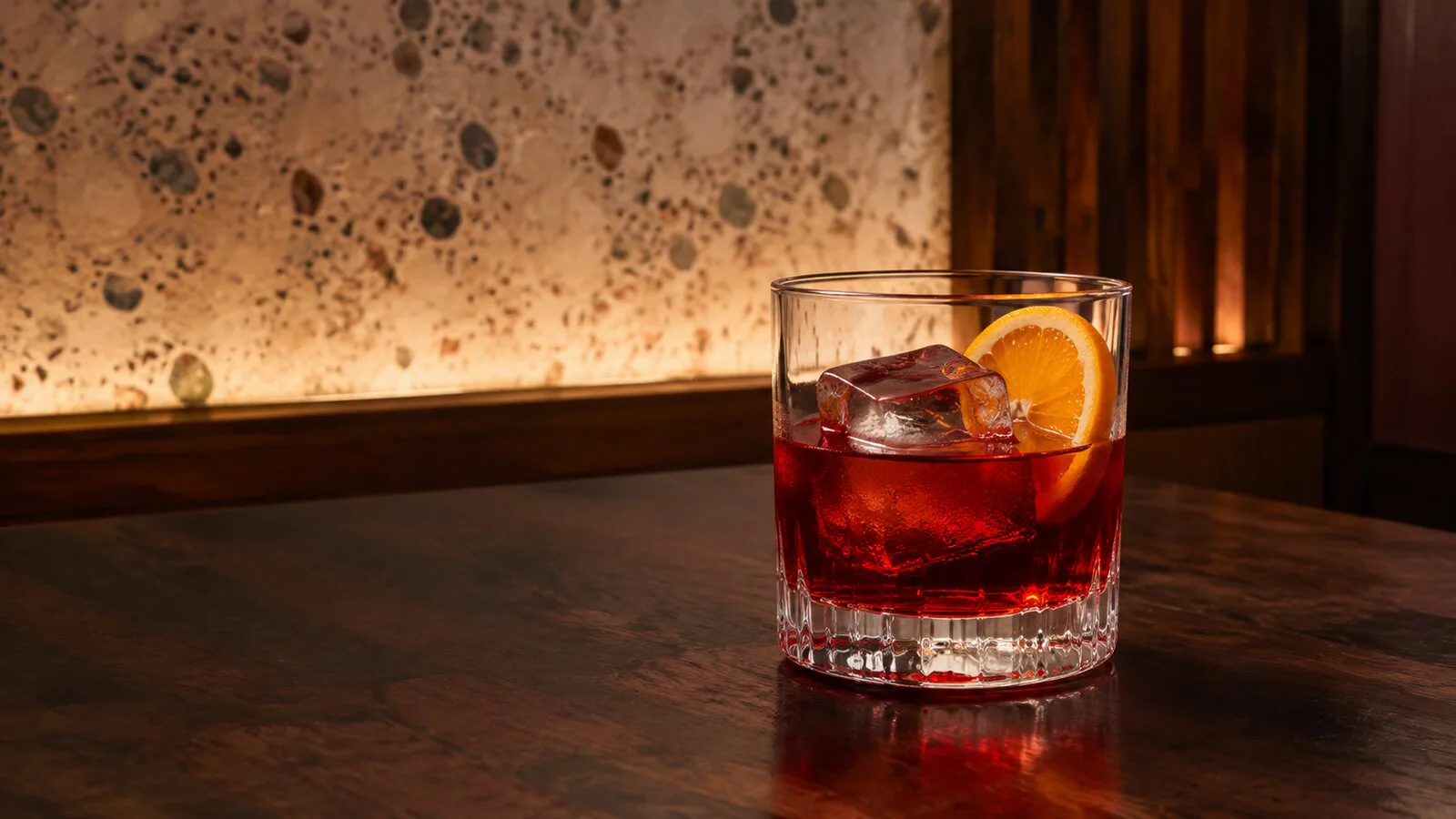 Negroni rojo servido en vaso bajo con hielo firme y naranja