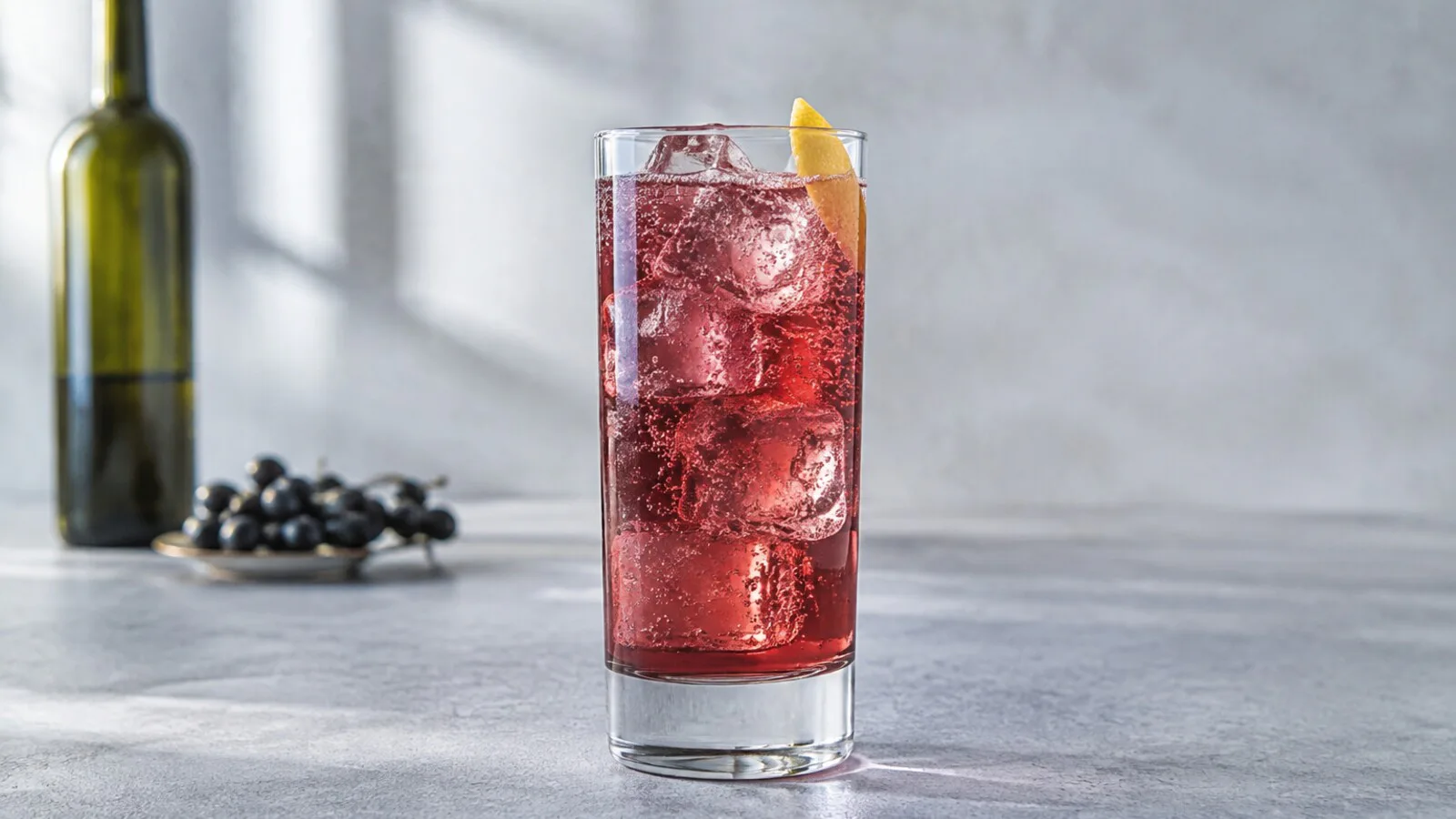 Pompier color rubí claro con vermut seco, crème de cassis, soda, hielo y piel de limón