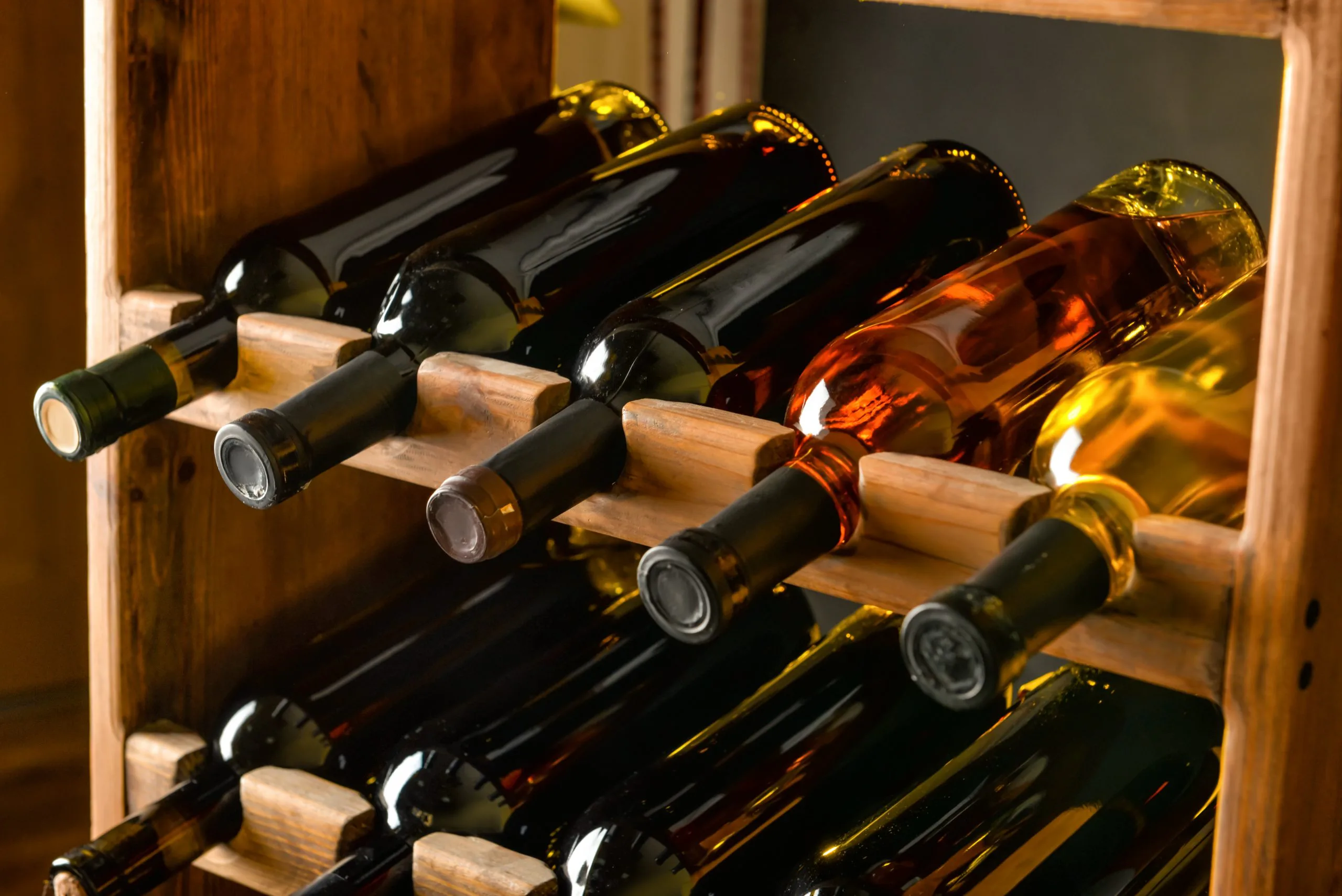 Botellas de vino guardadas en estantería para consumo futuro y evolución en botella