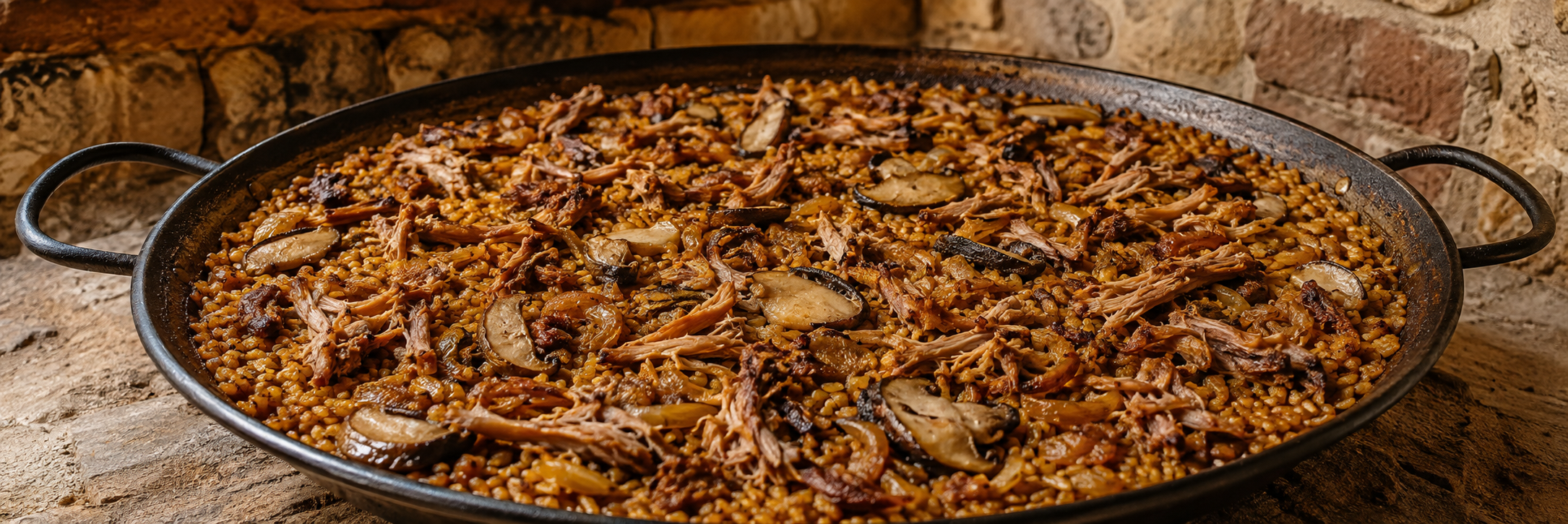 Arroz seco de pulled pork, cebolla caramelizada y boletus servido en paella