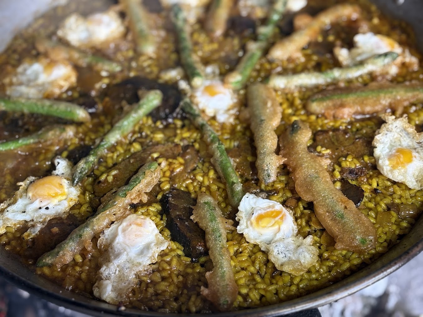 Paella gourmet con carrillada ibérica desmenuzada, tempura de espárragos crujientes y huevos de codorniz fritos