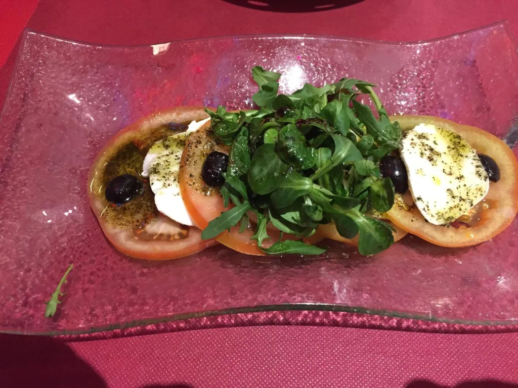 Ensalada caprese con aceitunas y tomates grandes carnosos lista para servir